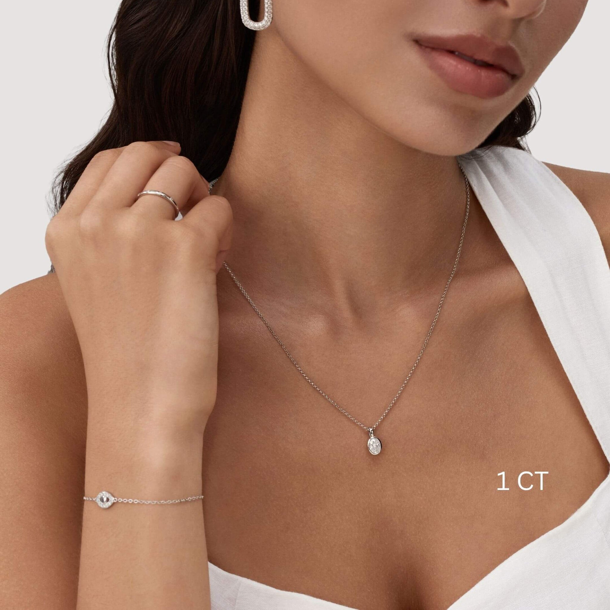 Oval-cut moissanite bezel pendant necklace worn at the neckline.