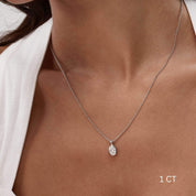 Oval-cut moissanite bezel pendant necklace worn at the neckline.