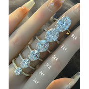 Oval-cut moissanite hidden halo ring with pavé band rings arranged across fingers for a carat-size comparison.