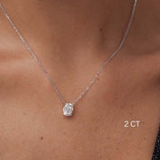 Oval-cut moissanite pendant necklace worn at the neckline.