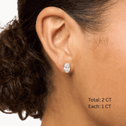 Oval-cut moissanite stud earrings worn on the ear, 2 ct per pair with 1 ct per stone.