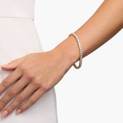 Oval-cut moissanite tennis bracelet worn on the wrist.