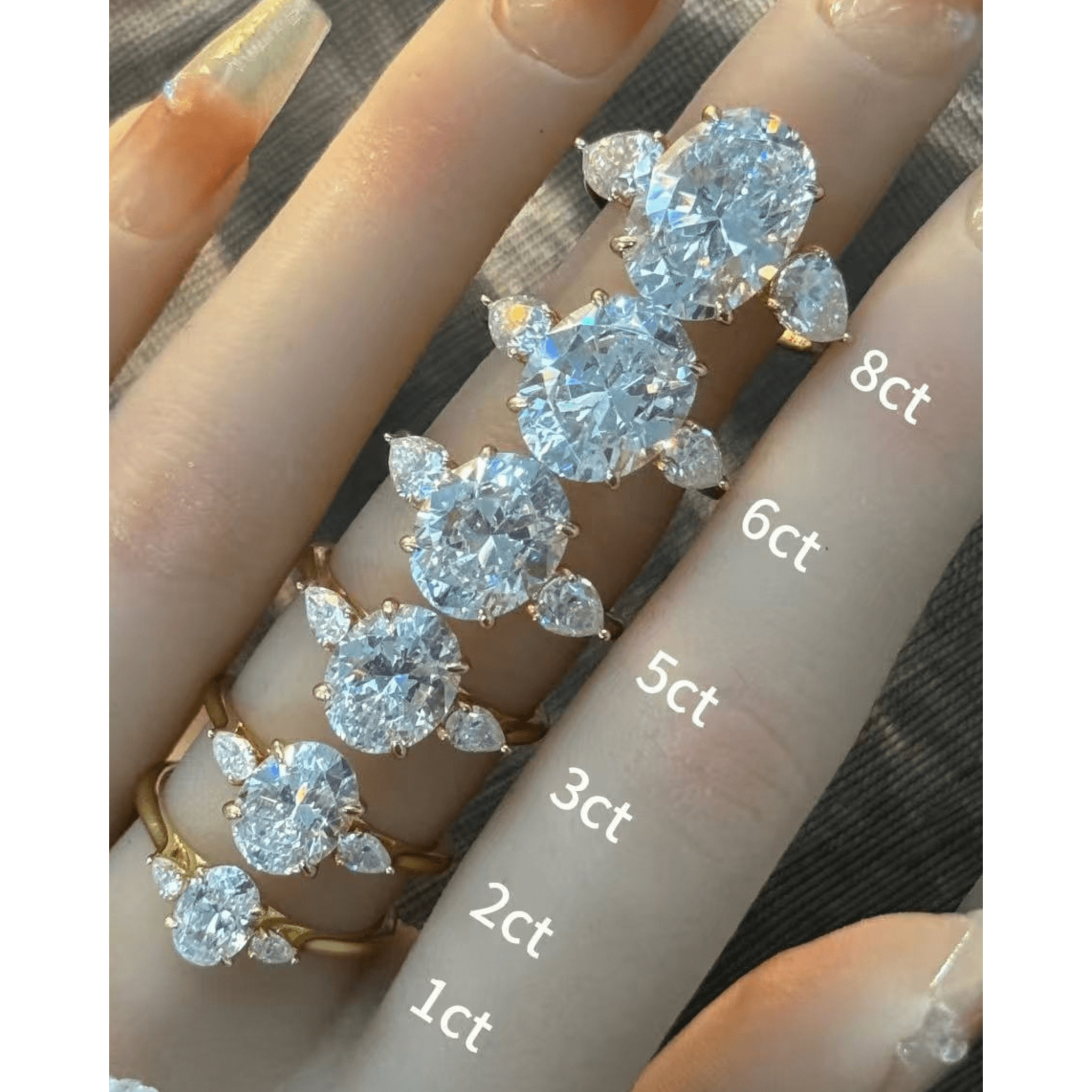 Oval-cut moissanite three-stone ring rings arranged across fingers for a carat-size comparison.