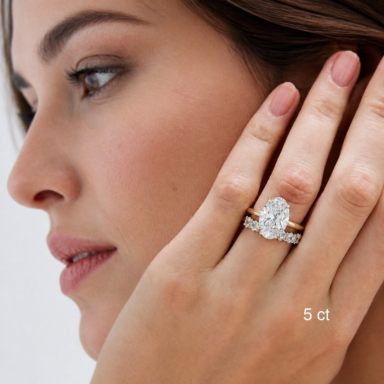 5 ct oval-cut moissanite ring in yellow gold worn with a stacking band