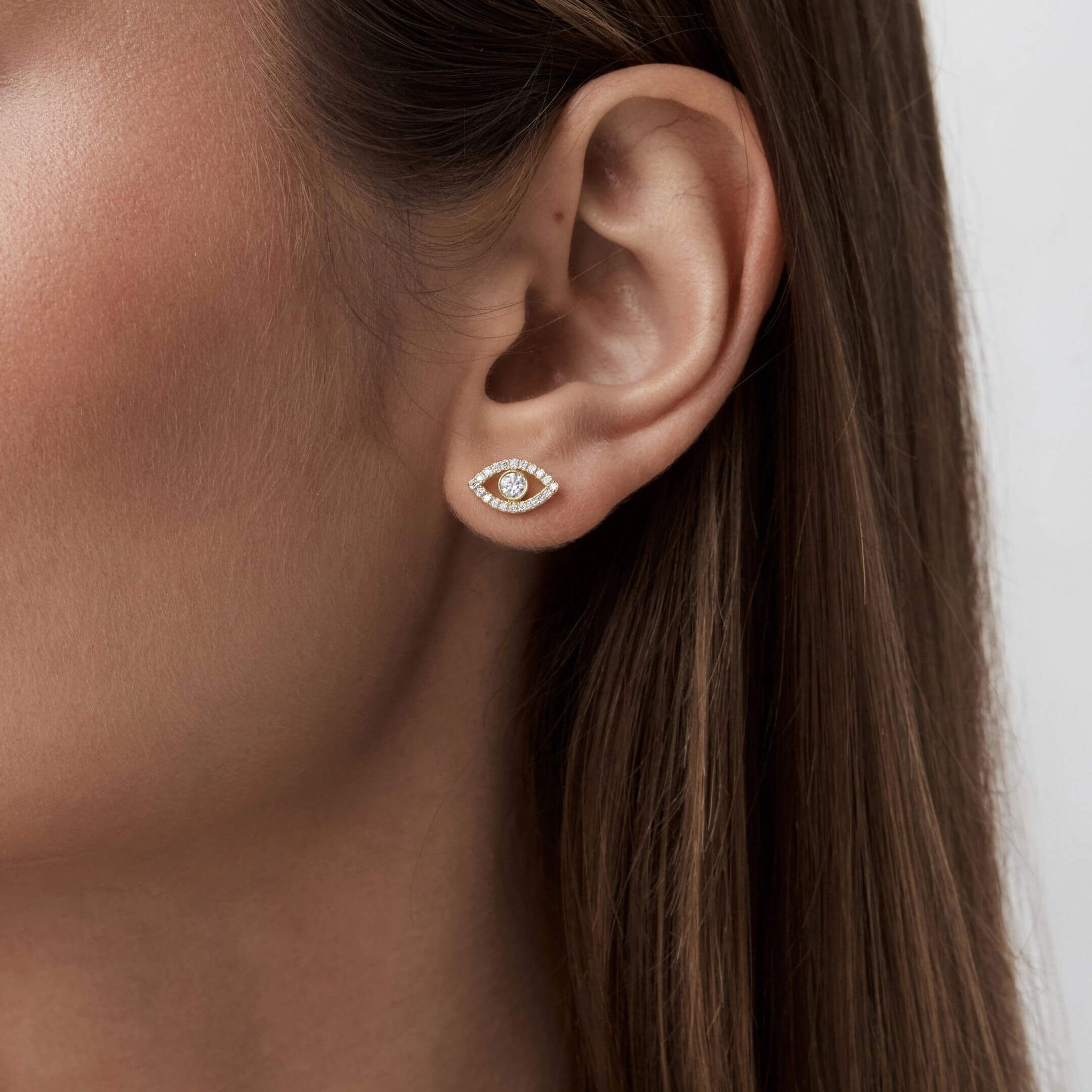 Pavé moissanite evil eye stud earrings worn on the ear.