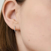 Pavé moissanite huggie hoop earrings worn on the ear.