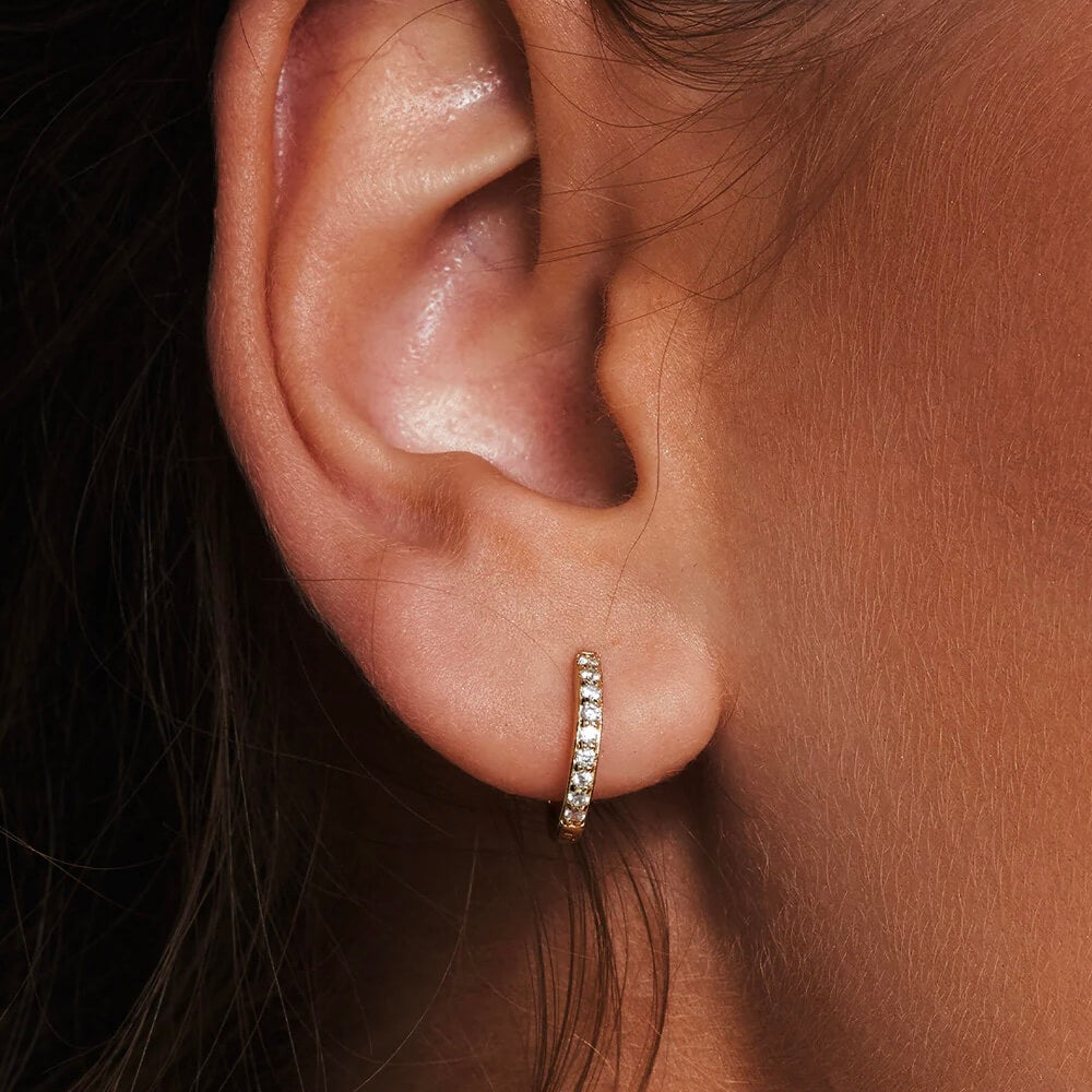 Pavé moissanite huggie hoop earrings worn on the ear.