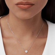 Pavé moissanite round pendant necklace worn at the neckline.
