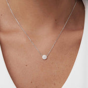 Pavé moissanite round pendant necklace worn at the neckline.