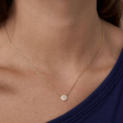 Pavé moissanite round pendant necklace worn at the neckline.