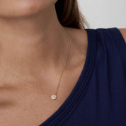 Pavé moissanite round pendant necklace worn at the neckline.