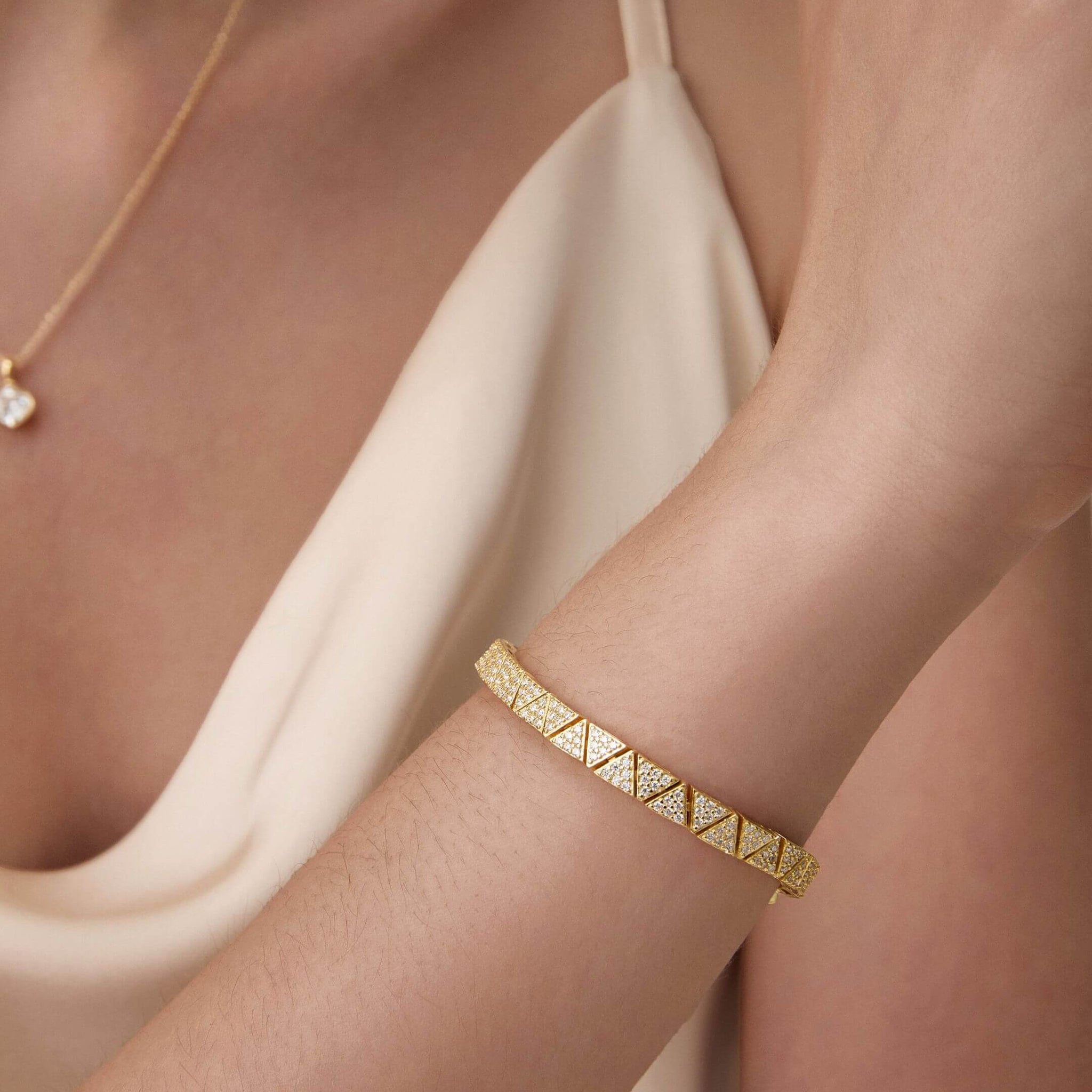 Pavé moissanite triangle-link tennis bracelet worn on the wrist.