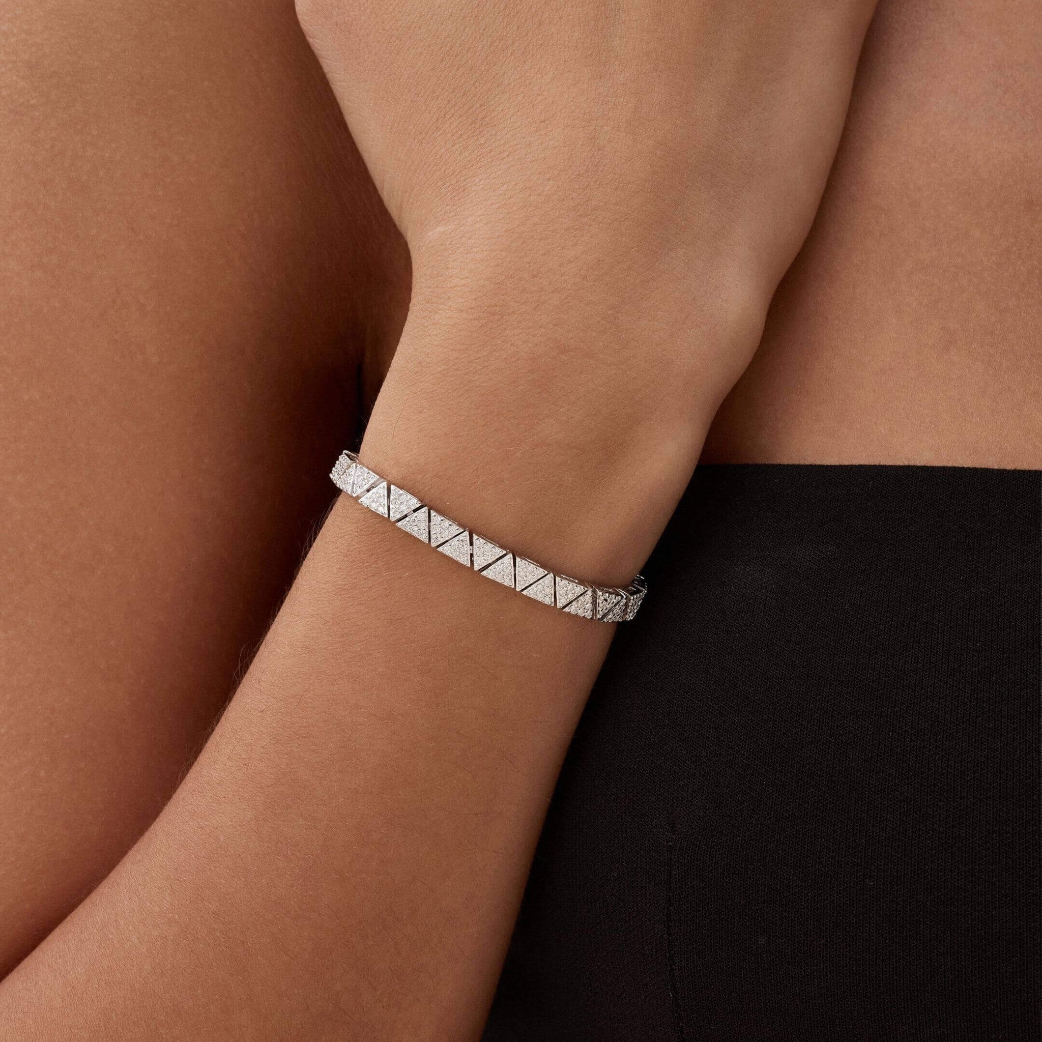 Pavé moissanite triangle-link tennis bracelet worn on the wrist.