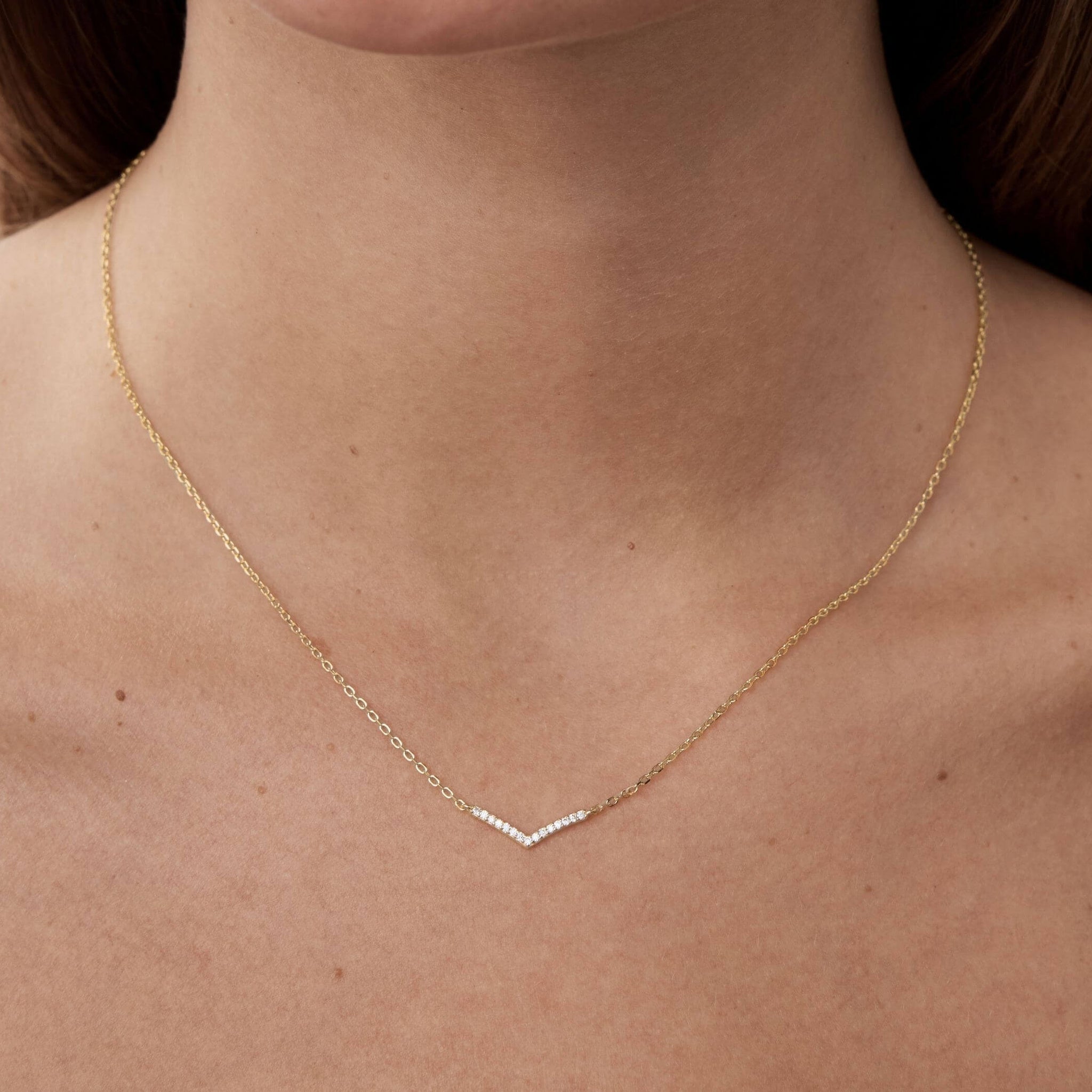 Pavé moissanite wishbone necklace worn at the neckline.