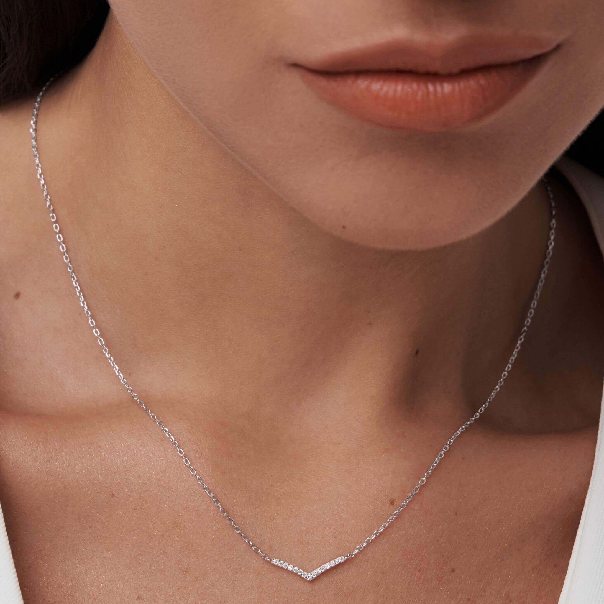 Pavé moissanite wishbone necklace worn at the neckline.
