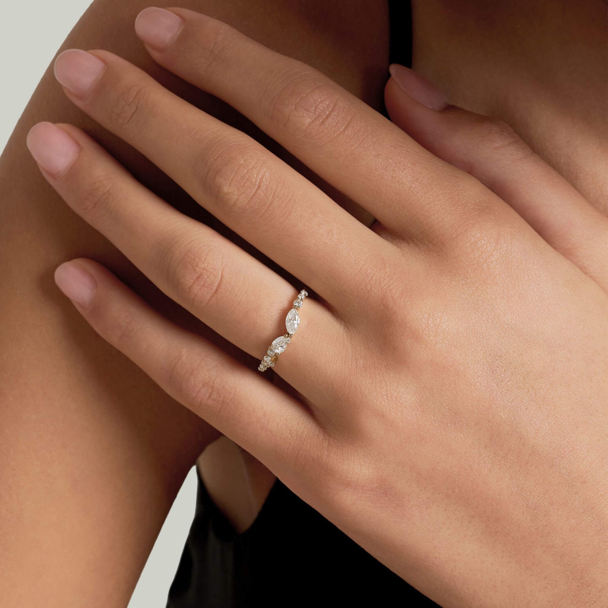 Pear-cut and marquise-cut moissanite cluster ring worn on a finger.