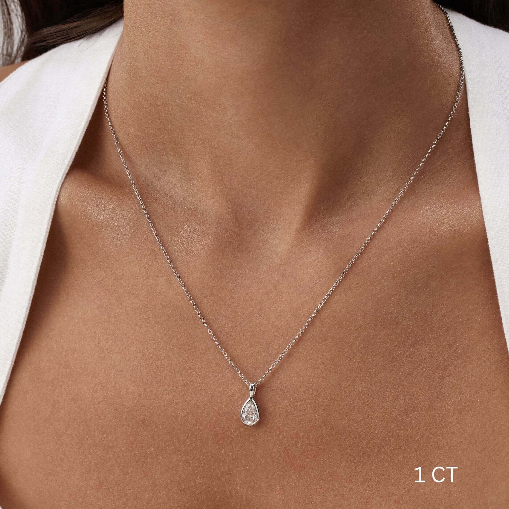 Pear-cut moissanite bezel pendant necklace worn at the neckline.