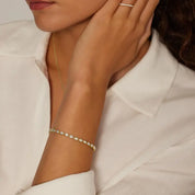 Pear-cut moissanite bezel tennis bracelet worn on the wrist.