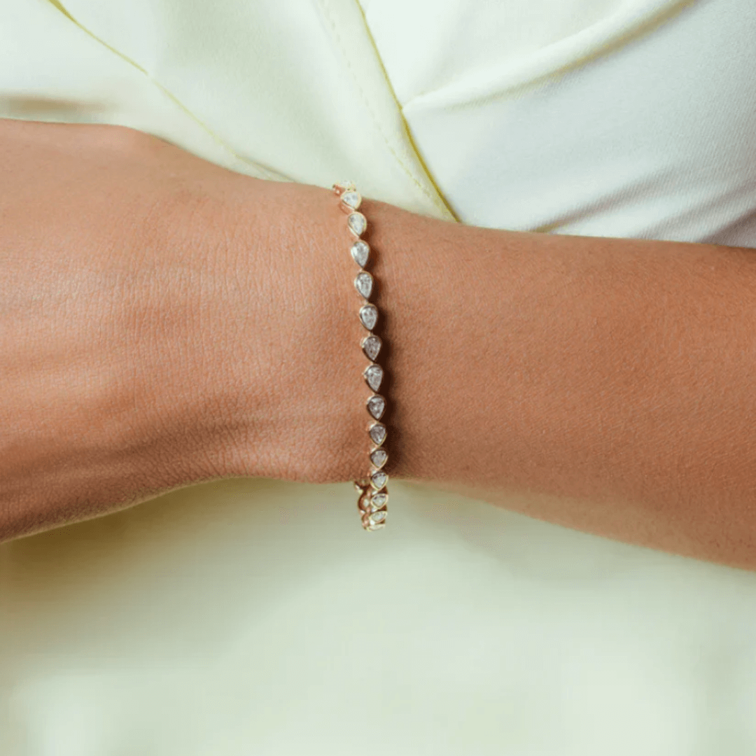 Pear-cut moissanite bezel tennis bracelet worn on the wrist.