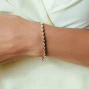 Pear-cut moissanite bezel tennis bracelet worn on the wrist.