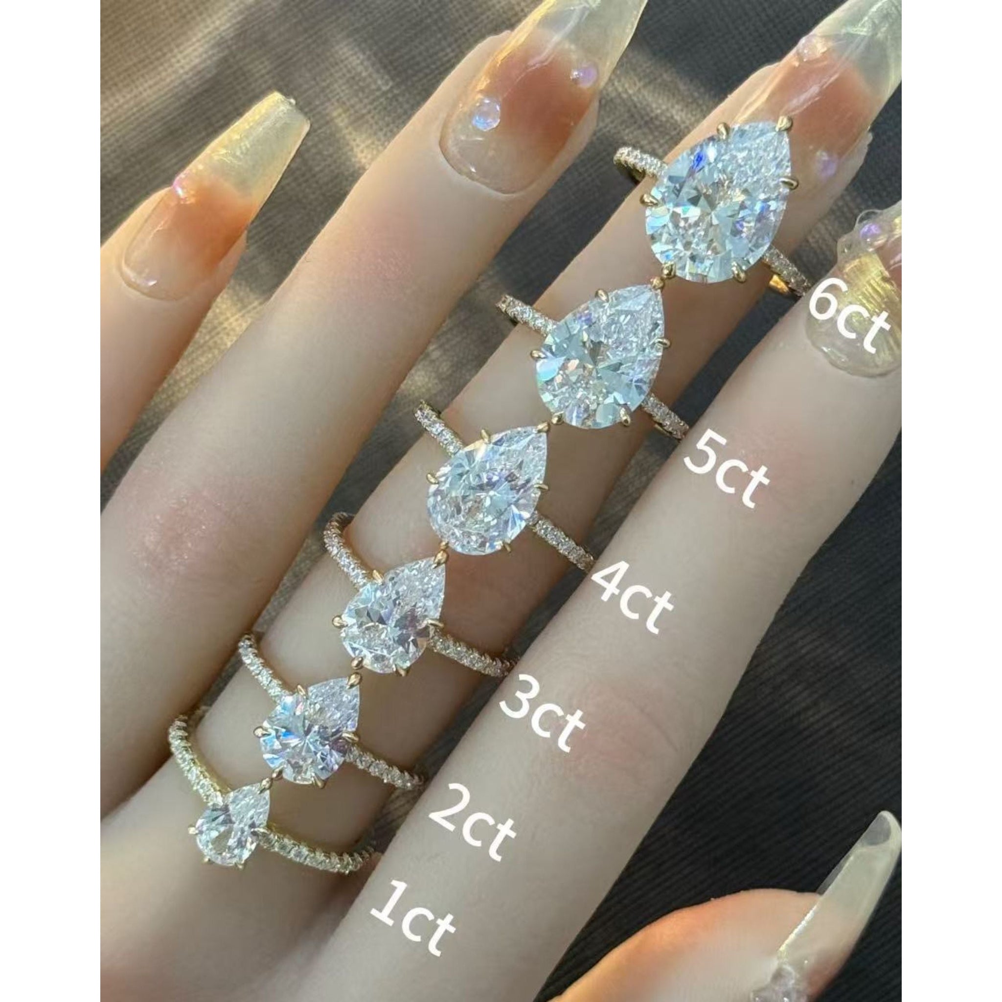 Pear-cut moissanite hidden halo ring with pavé band rings arranged across fingers for a carat-size comparison.