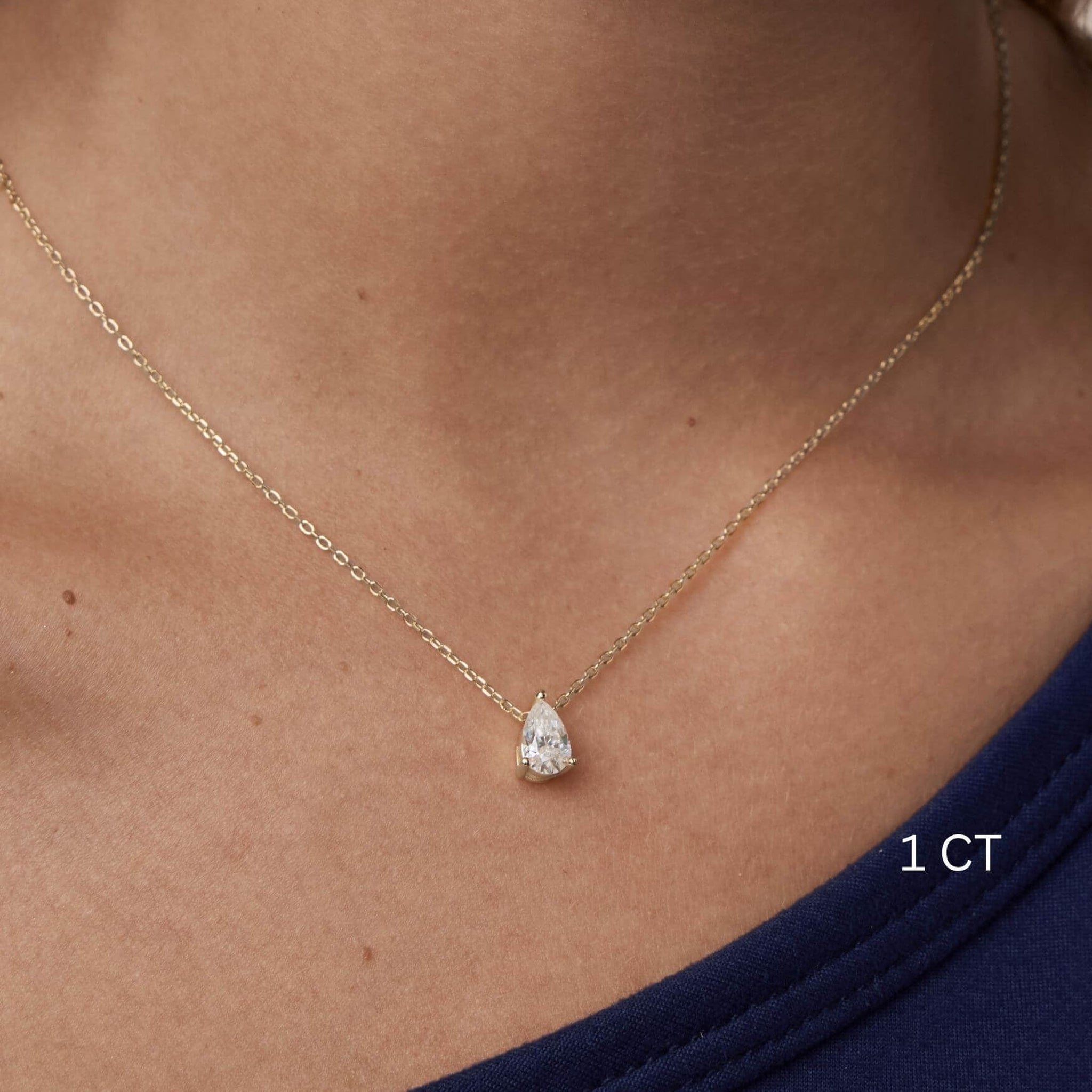 Pear-cut moissanite pendant necklace worn at the neckline.