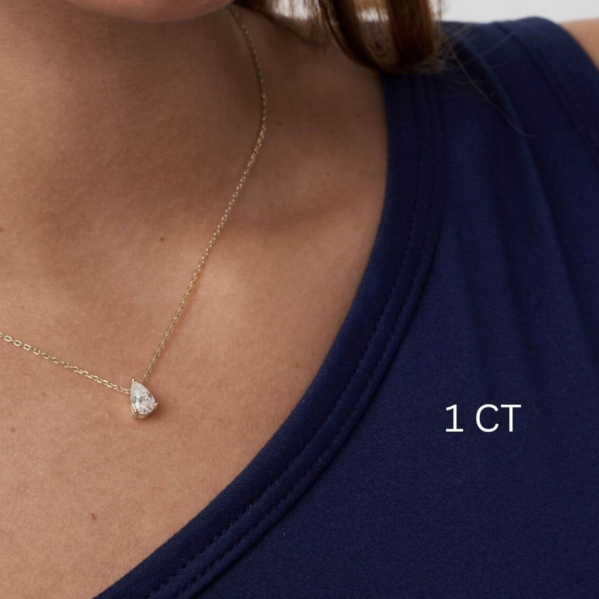 Pear-cut moissanite pendant necklace worn at the neckline.