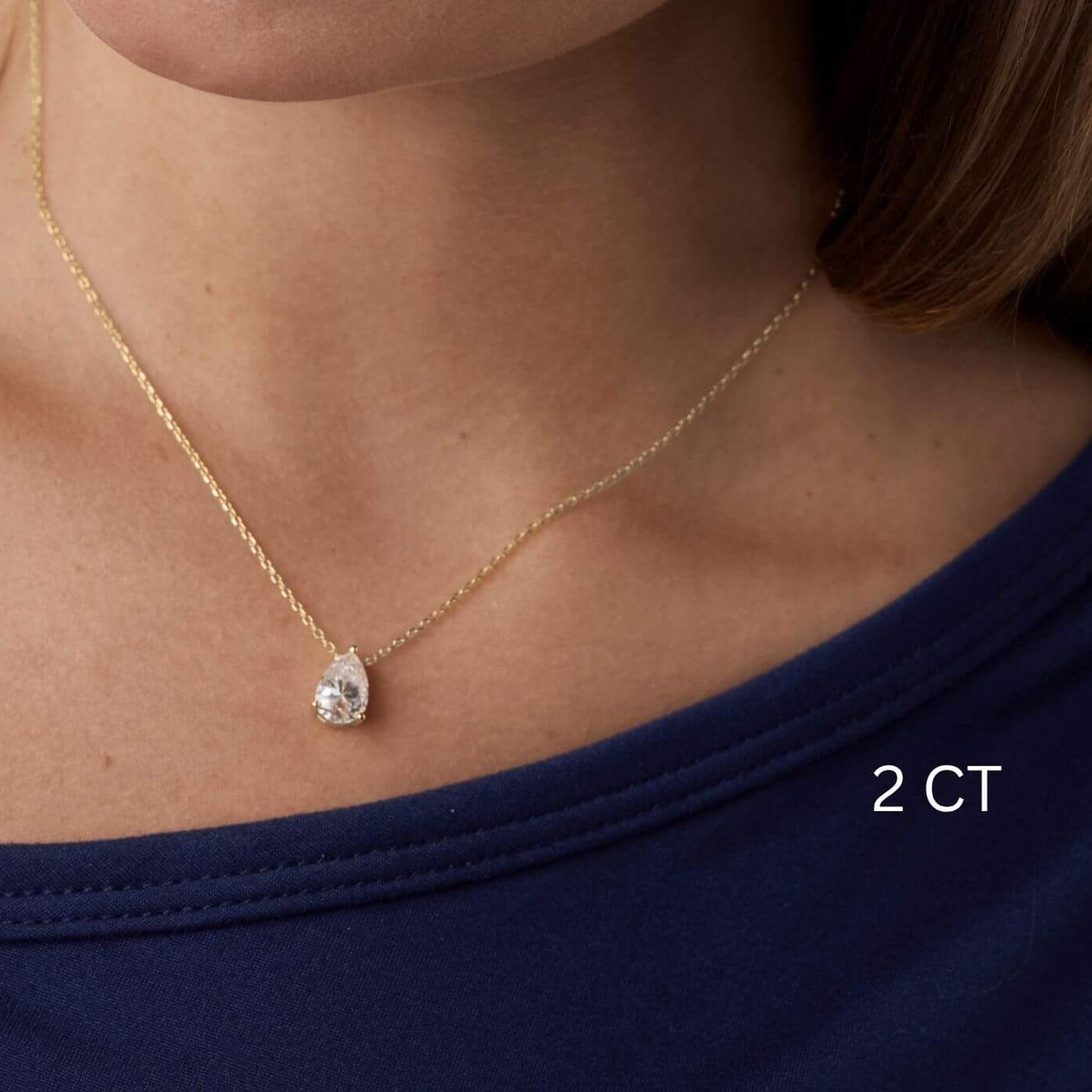 Pear-cut moissanite pendant necklace worn at the neckline.