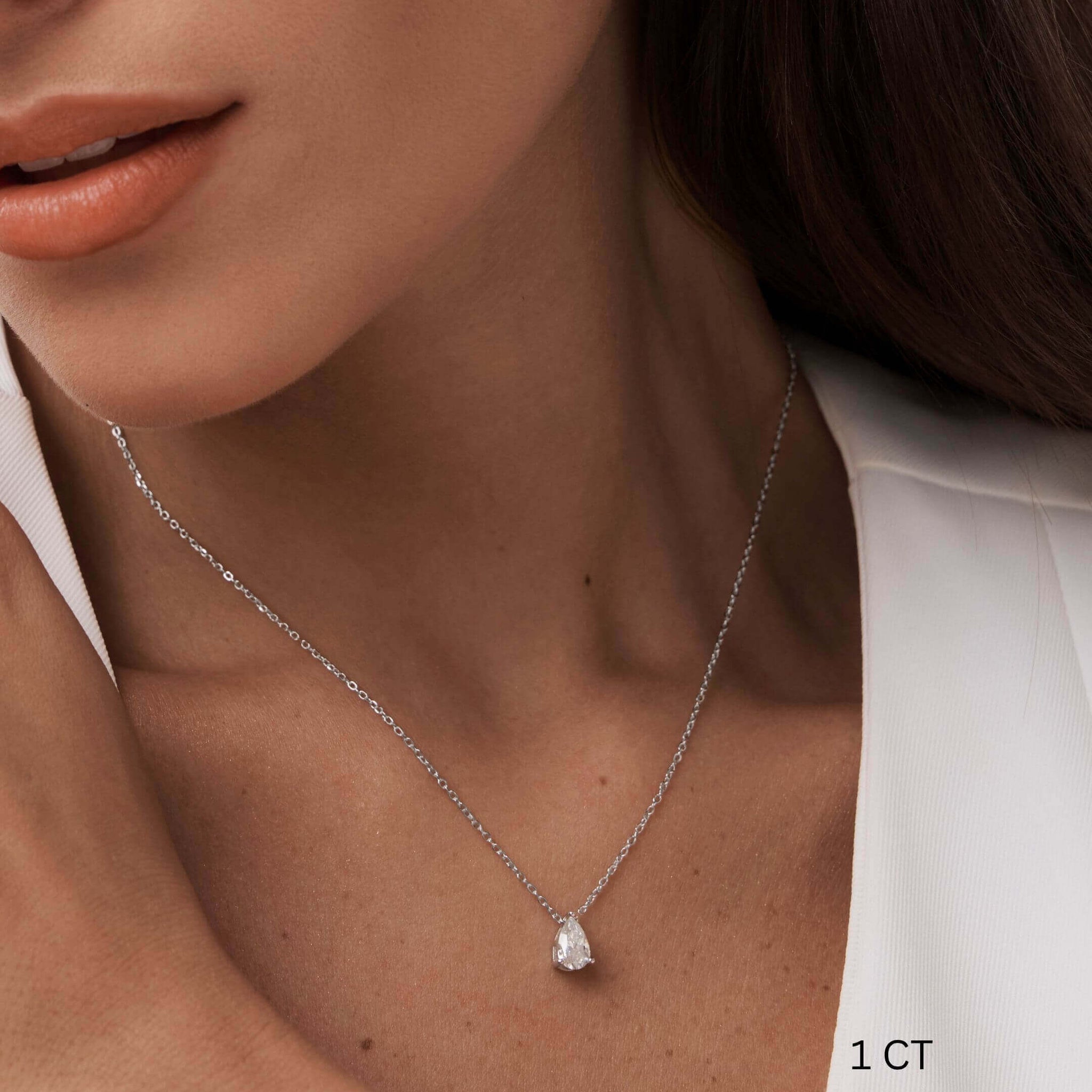 Pear-cut moissanite pendant necklace worn at the neckline.