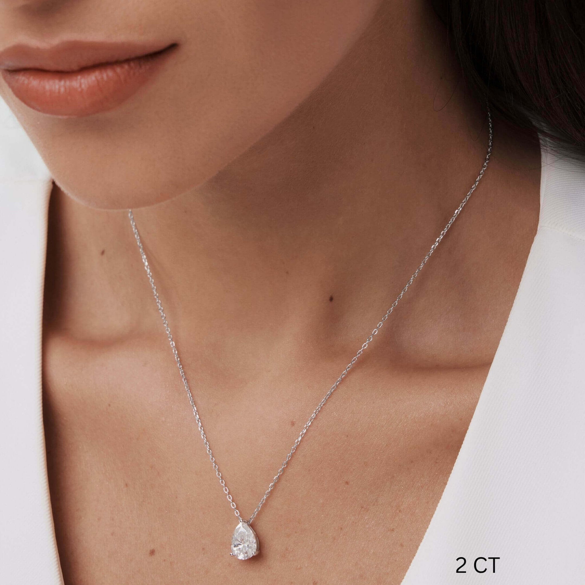 Pear-cut moissanite pendant necklace worn at the neckline.