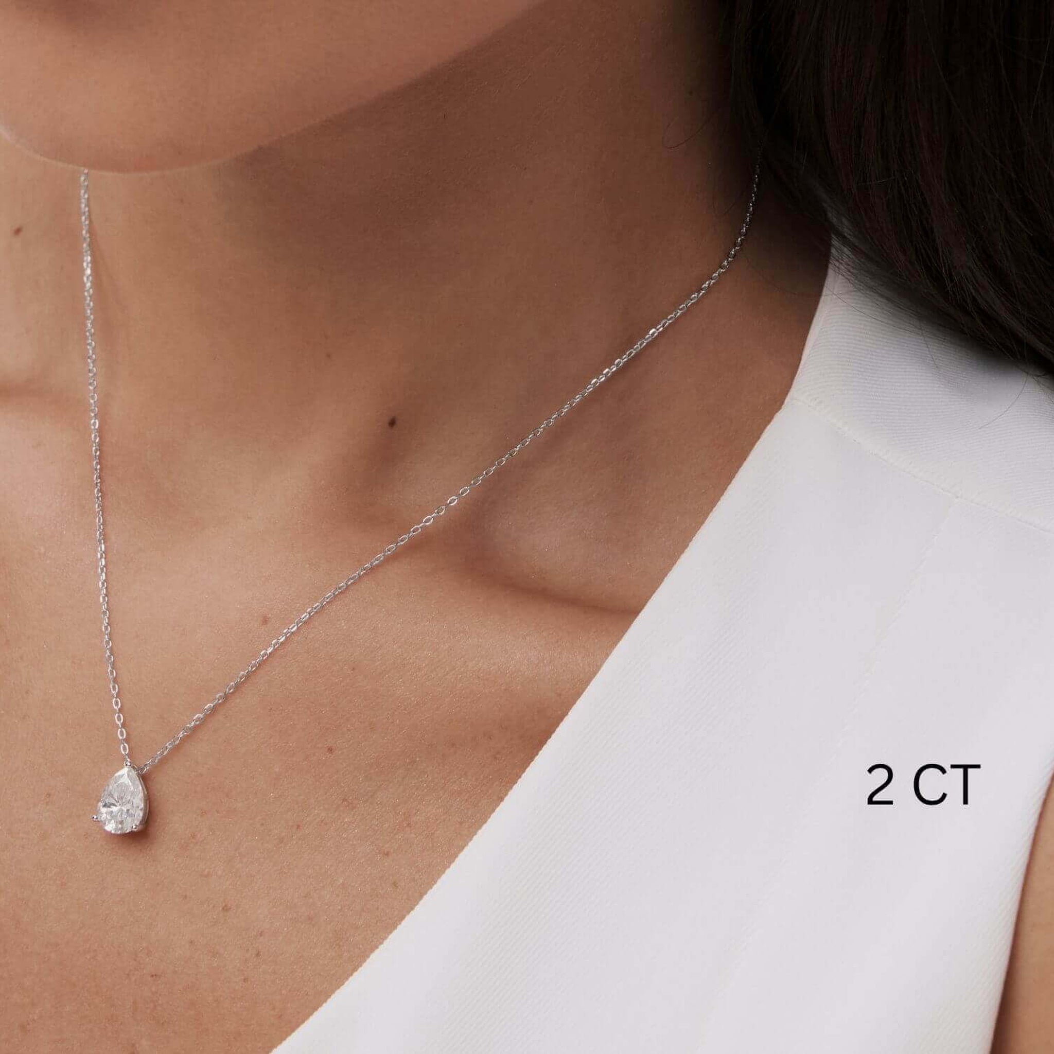 Pear-cut moissanite pendant necklace worn at the neckline.