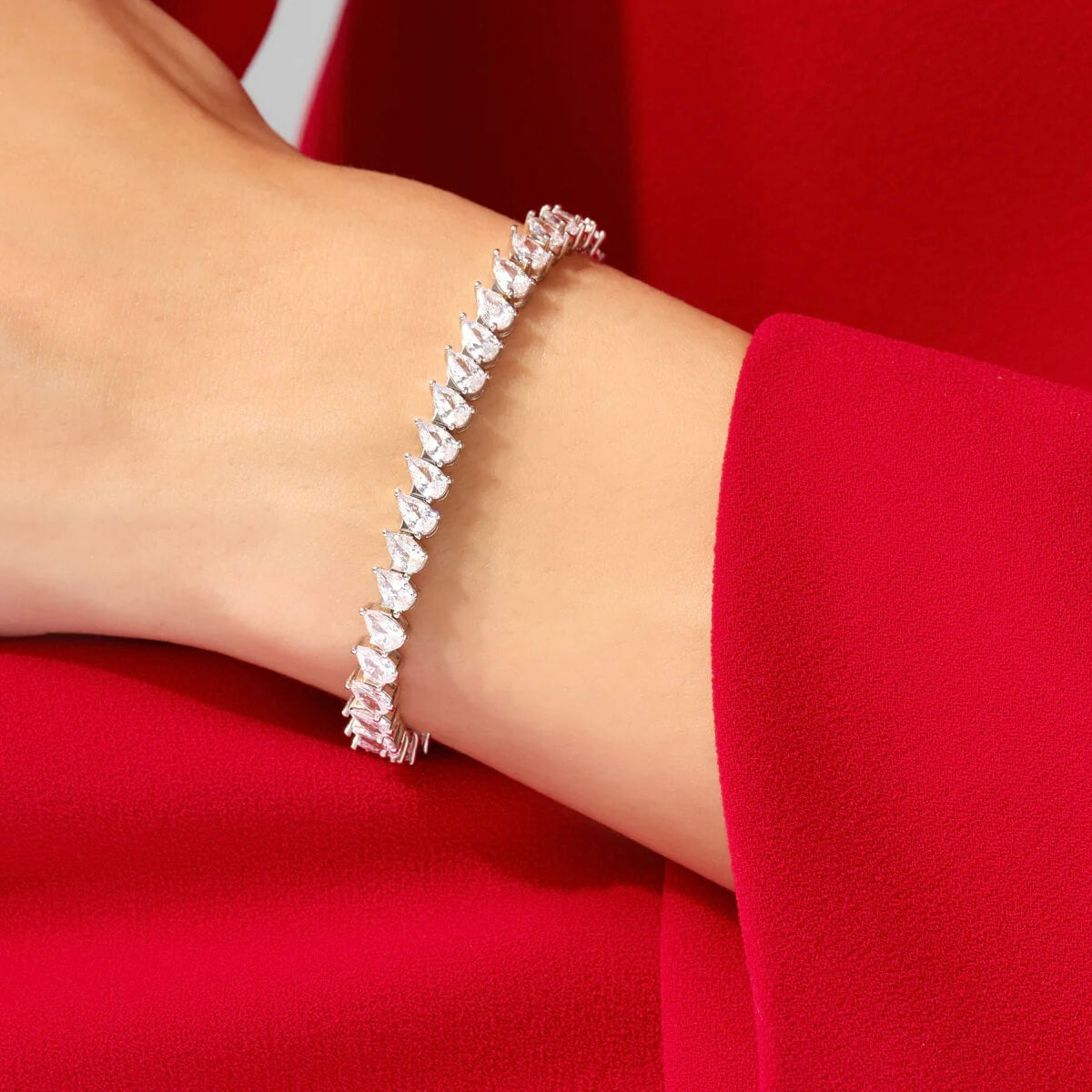 Pear-cut moissanite tennis bracelet worn on the wrist.