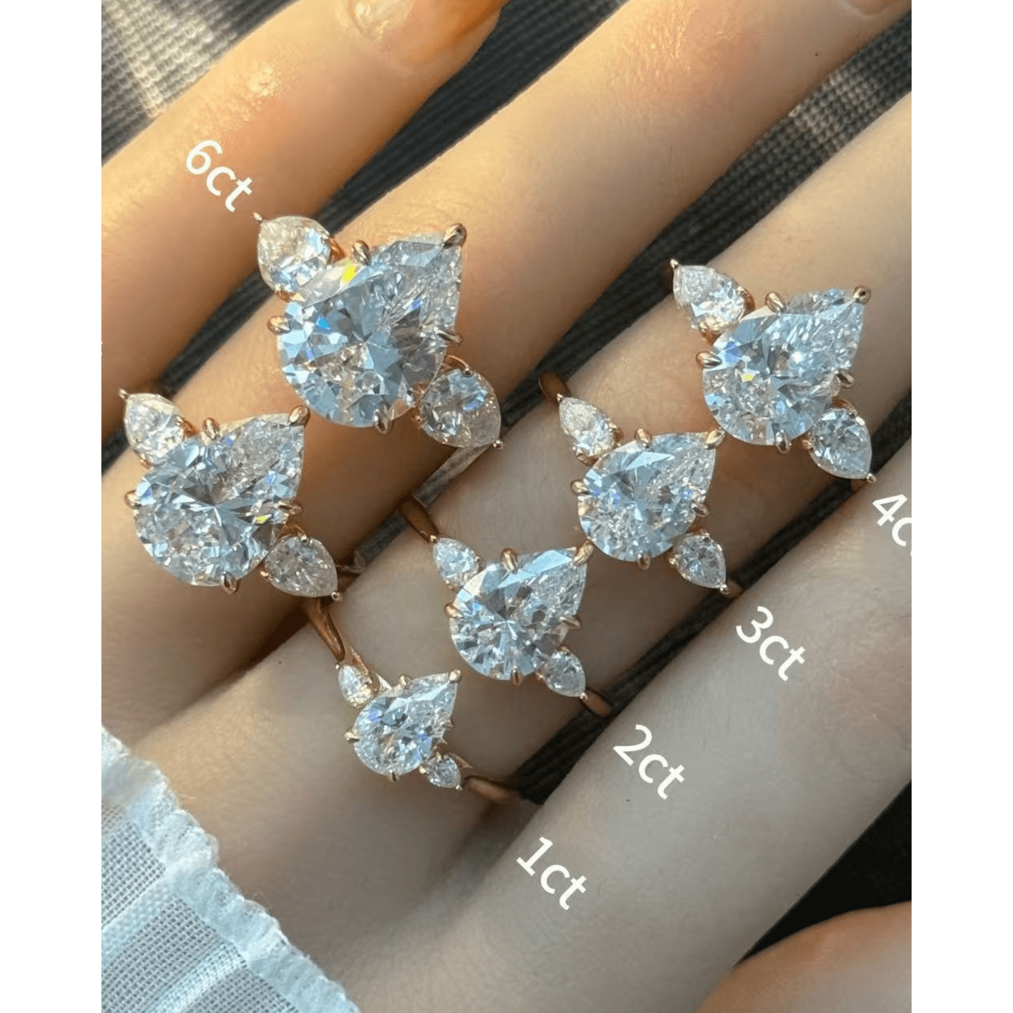Pear-cut moissanite three-stone ring rings arranged across fingers for a carat-size comparison.