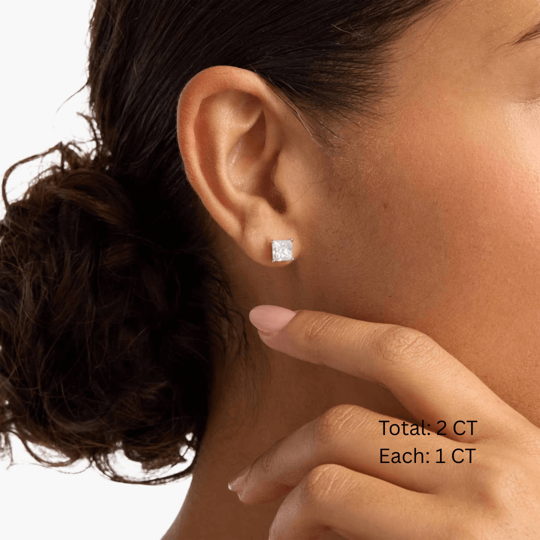 Princess-cut moissanite stud earrings worn on the ear, 2 ct per pair with 1 ct per stone.