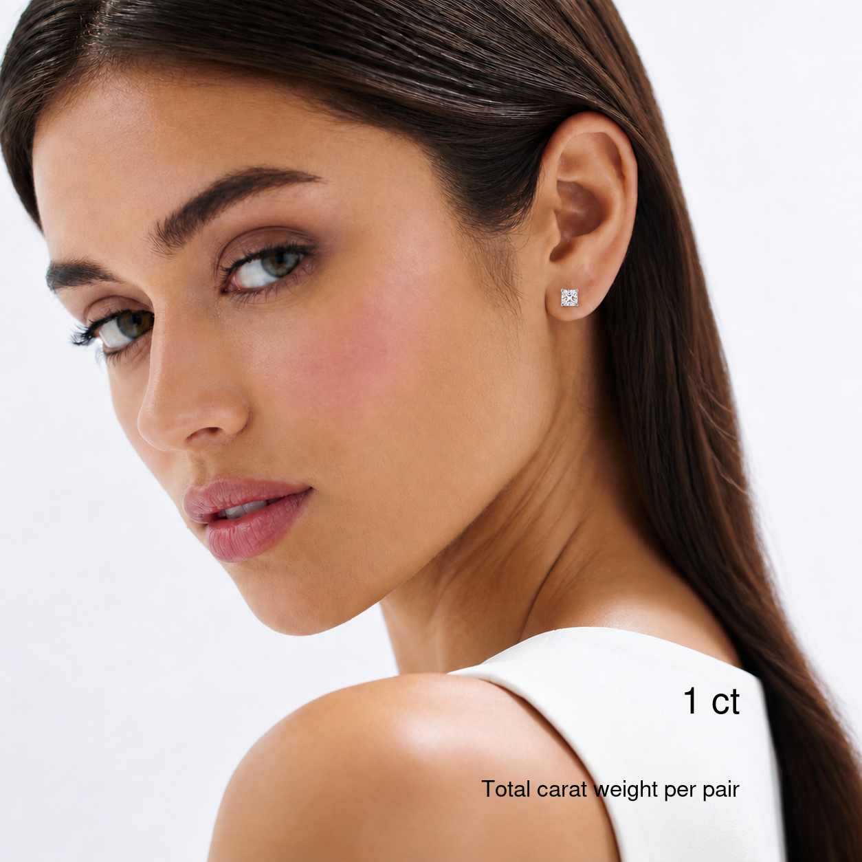 Princess-cut white gold stud earrings worn on a model, 1 ct total carat weight per pair.