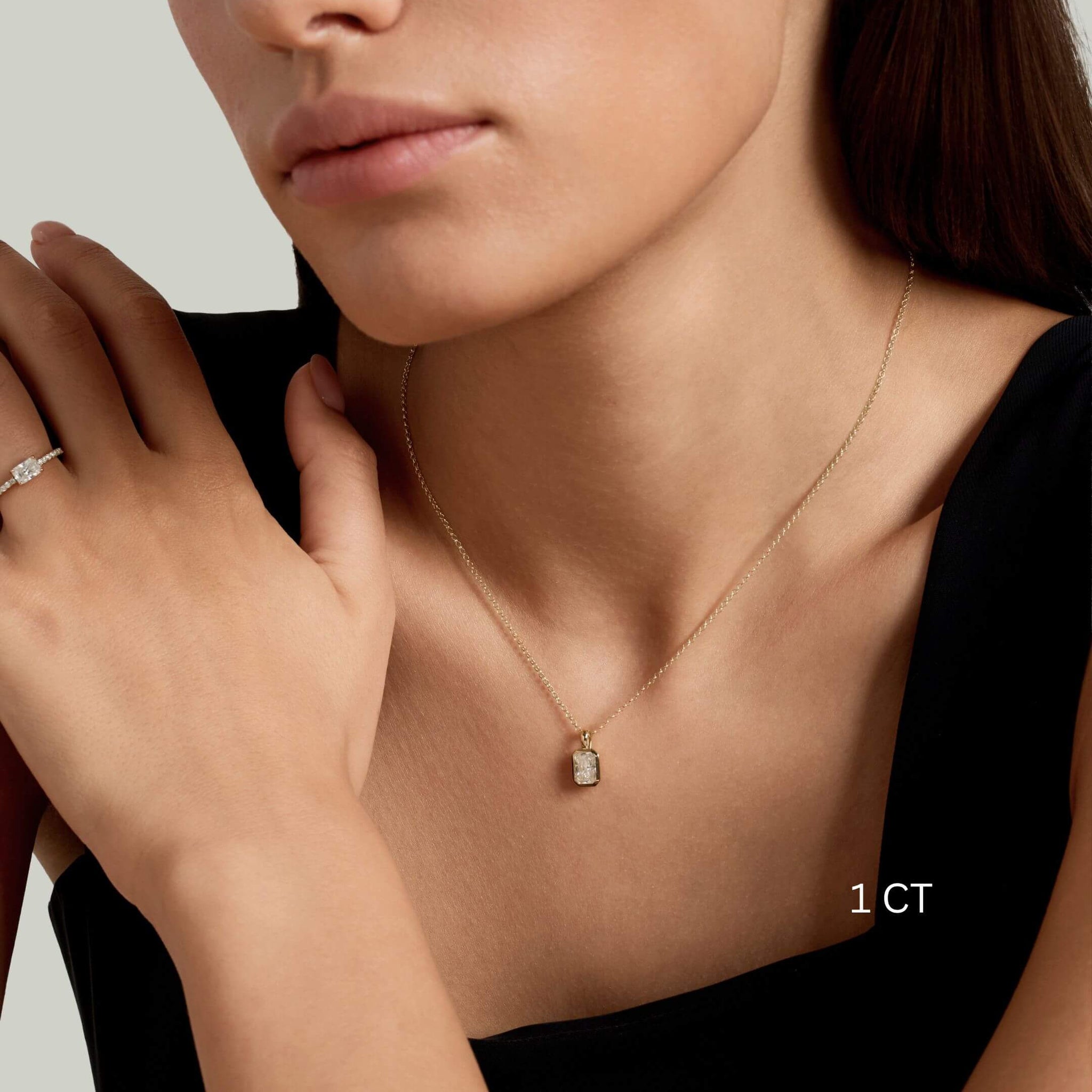Radiant-cut moissanite bezel pendant necklace worn at the neckline.