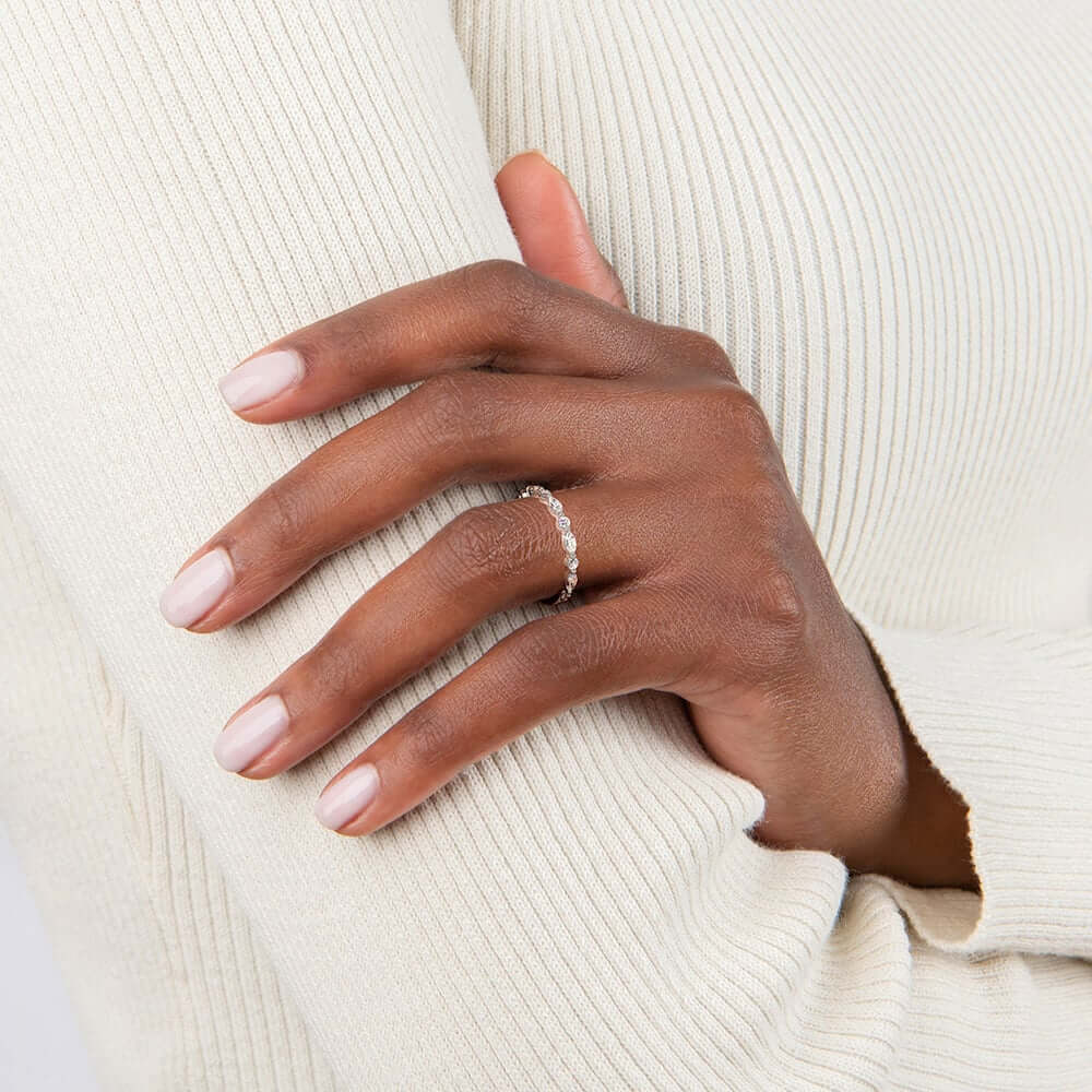 Round-cut and marquise-cut moissanite half eternity ring worn on a finger.