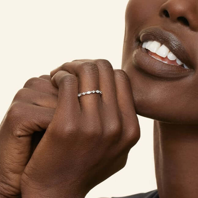 Round-cut and marquise-cut moissanite half eternity ring worn on a finger.