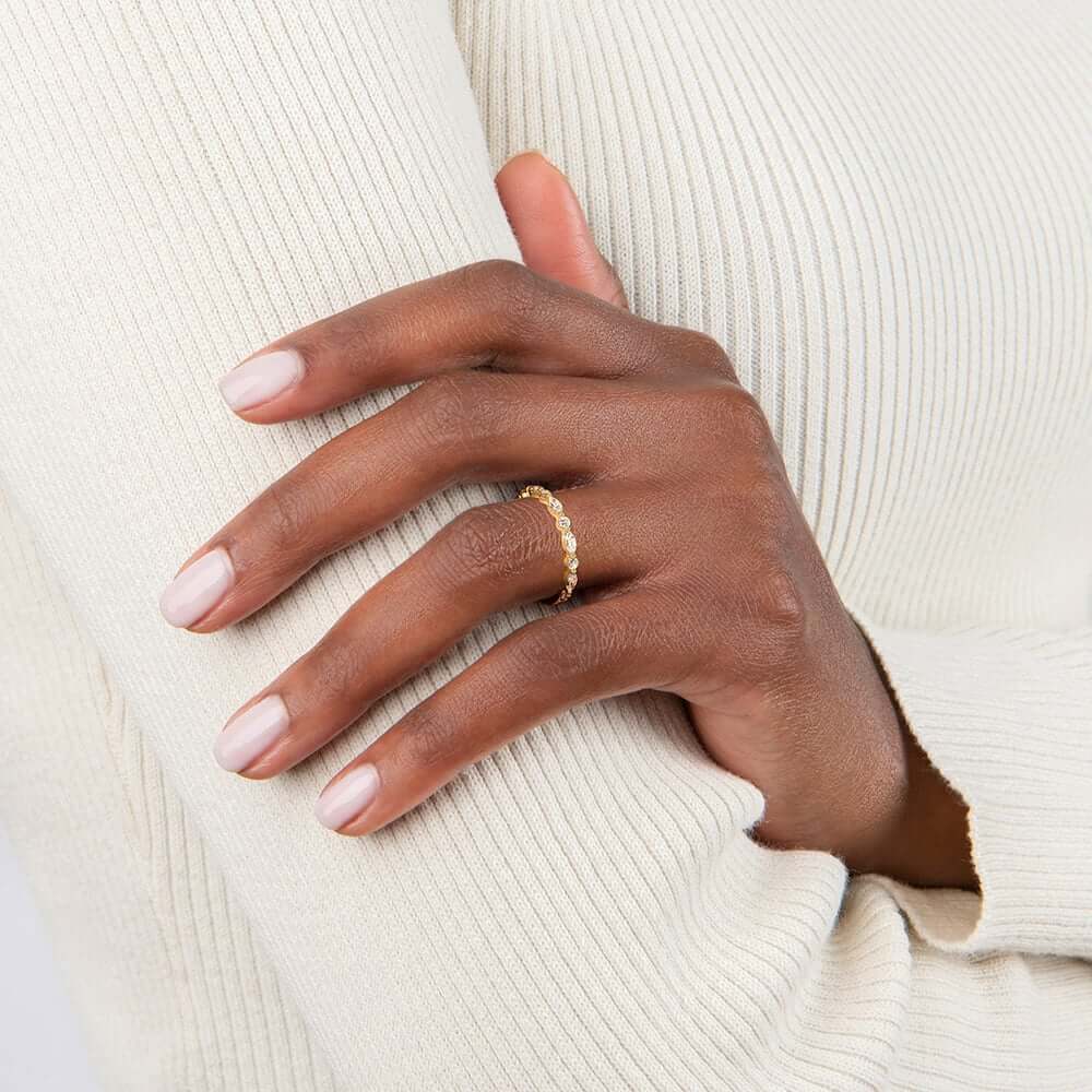Round-cut and marquise-cut moissanite half eternity ring worn on a finger.