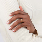 Round-cut and marquise-cut moissanite half eternity ring worn on a finger.