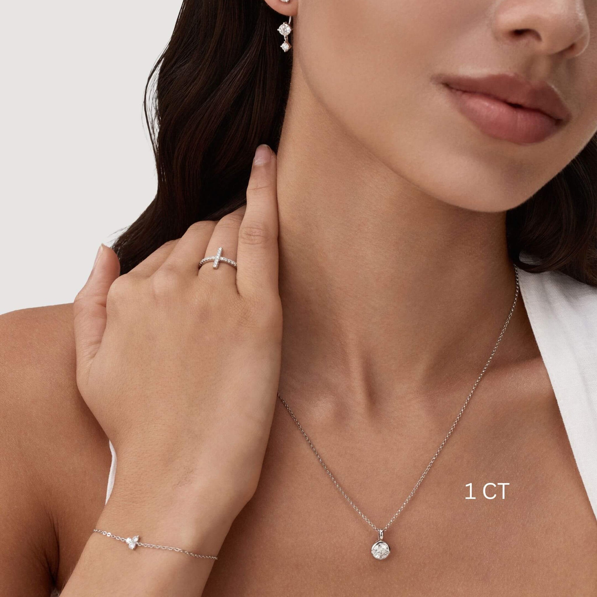 Round-cut moissanite bezel pendant necklace worn at the neckline.