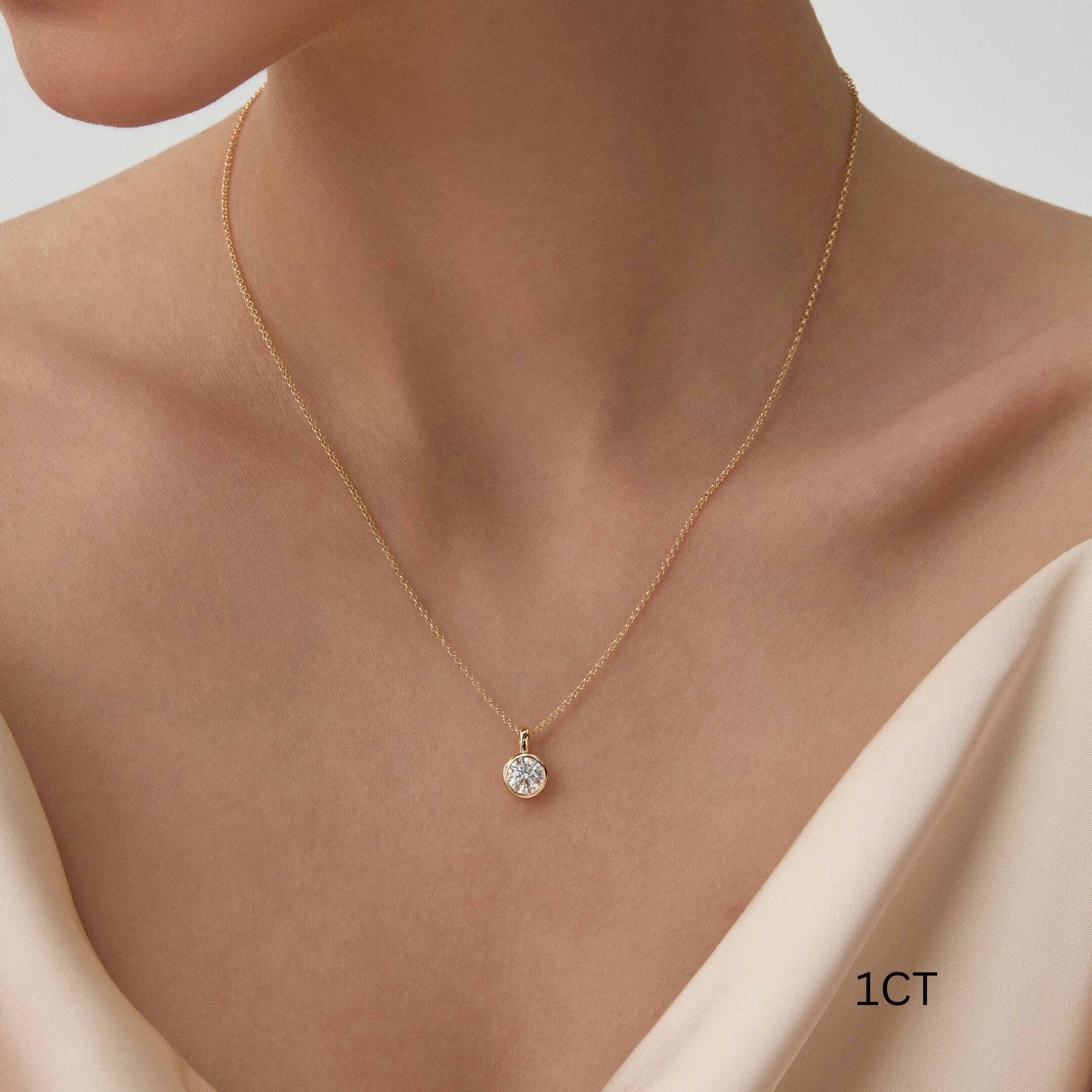 Round-cut moissanite bezel pendant necklace worn at the neckline.