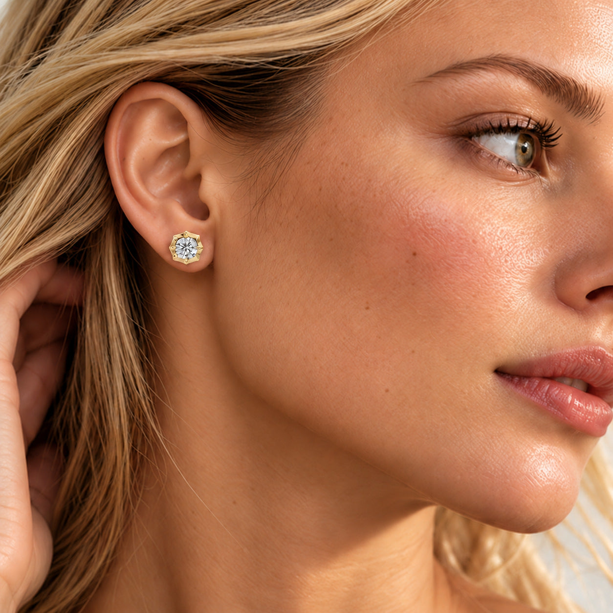 Close-up of a model wearing a round-cut moissanite bezel-prong stud earring in 18k yellow gold vermeil.
