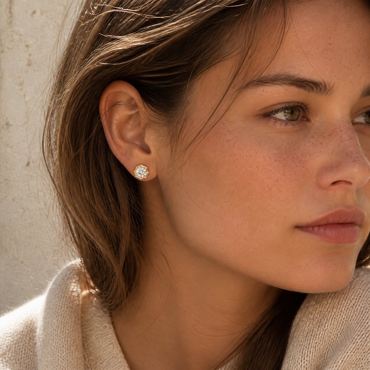 Round-cut moissanite bezel-prong stud earrings in yellow gold vermeil, worn by a model.