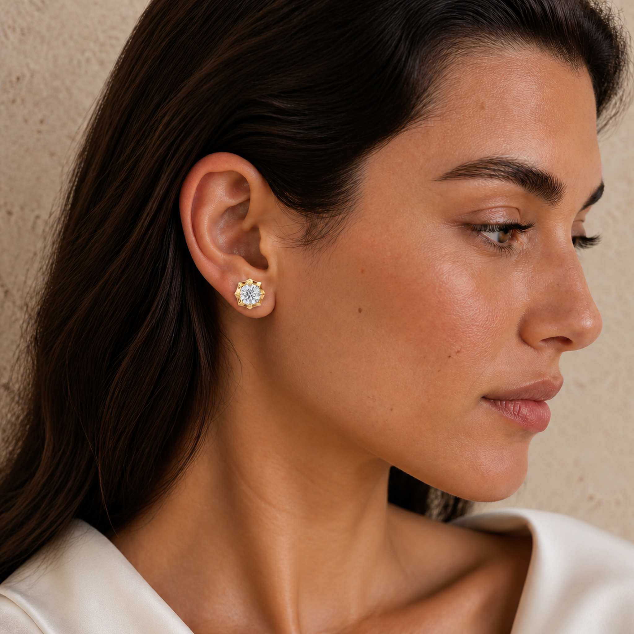 Round-cut moissanite bezel-prong stud earring in yellow gold vermeil, worn on the earlobe.