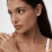 Round-cut moissanite cushion halo stud earrings worn on the ear.