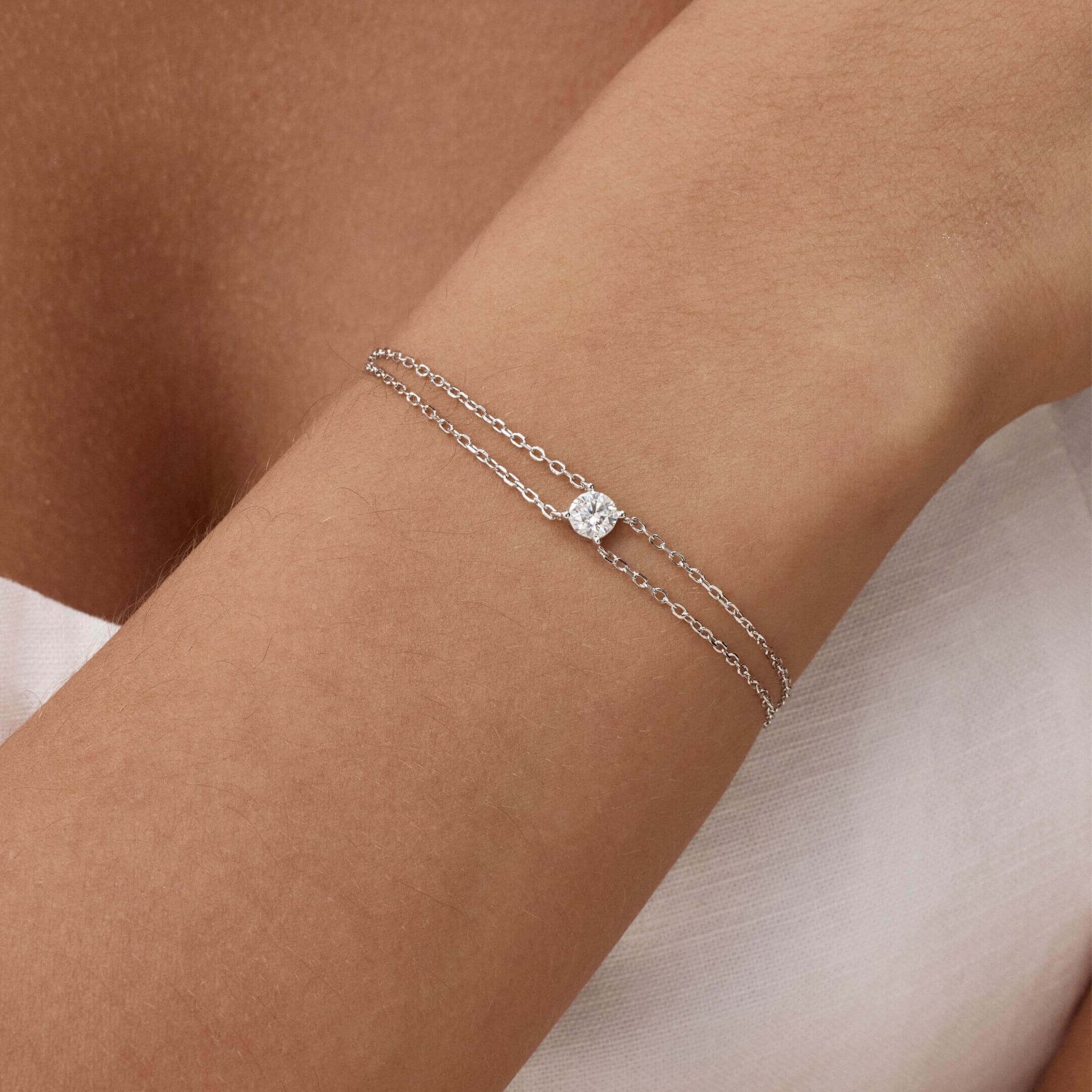 Round-cut moissanite double-chain bracelet worn on the wrist.