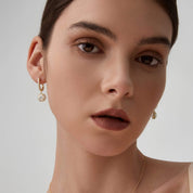 Round-cut moissanite halo drop earrings worn on the ear.