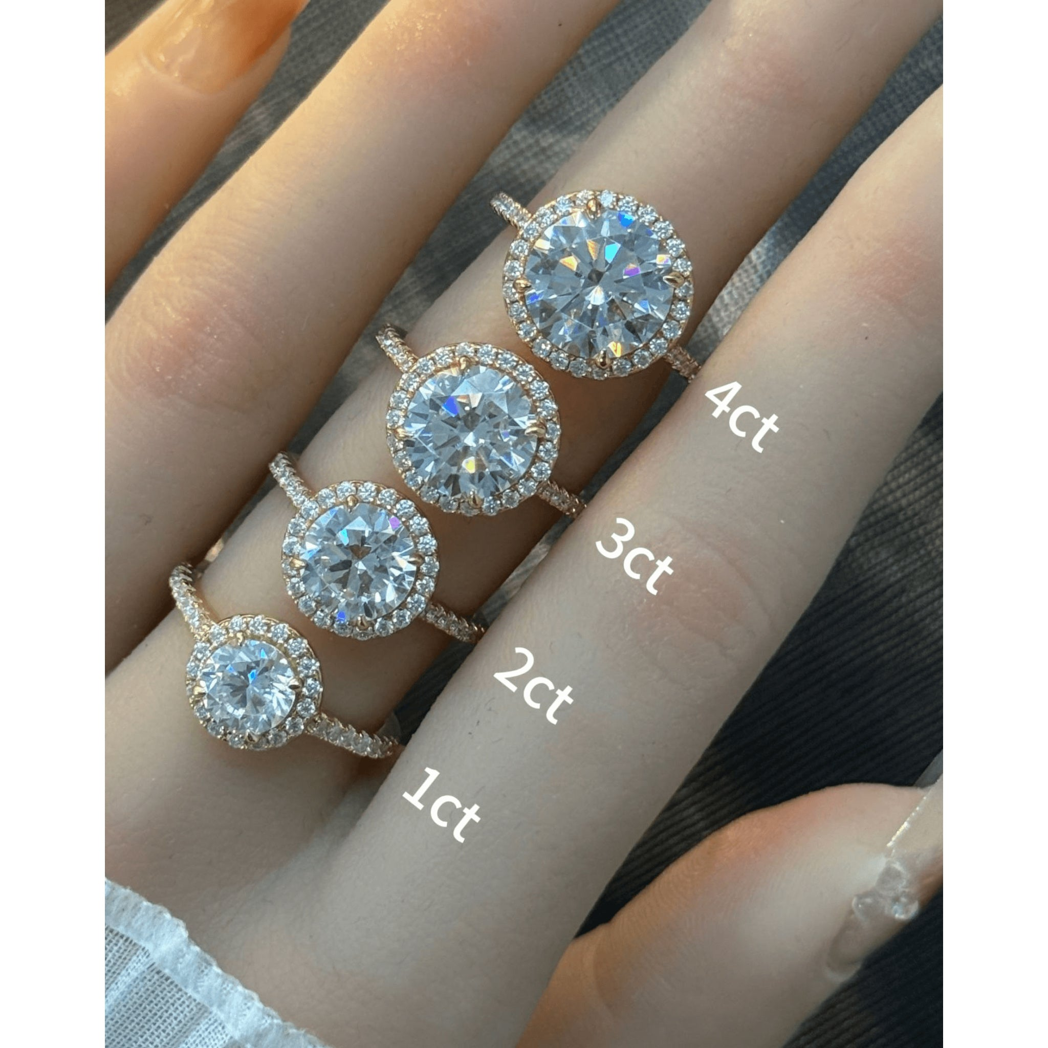Round-cut moissanite halo ring with pavé band rings arranged across fingers for a carat-size comparison.