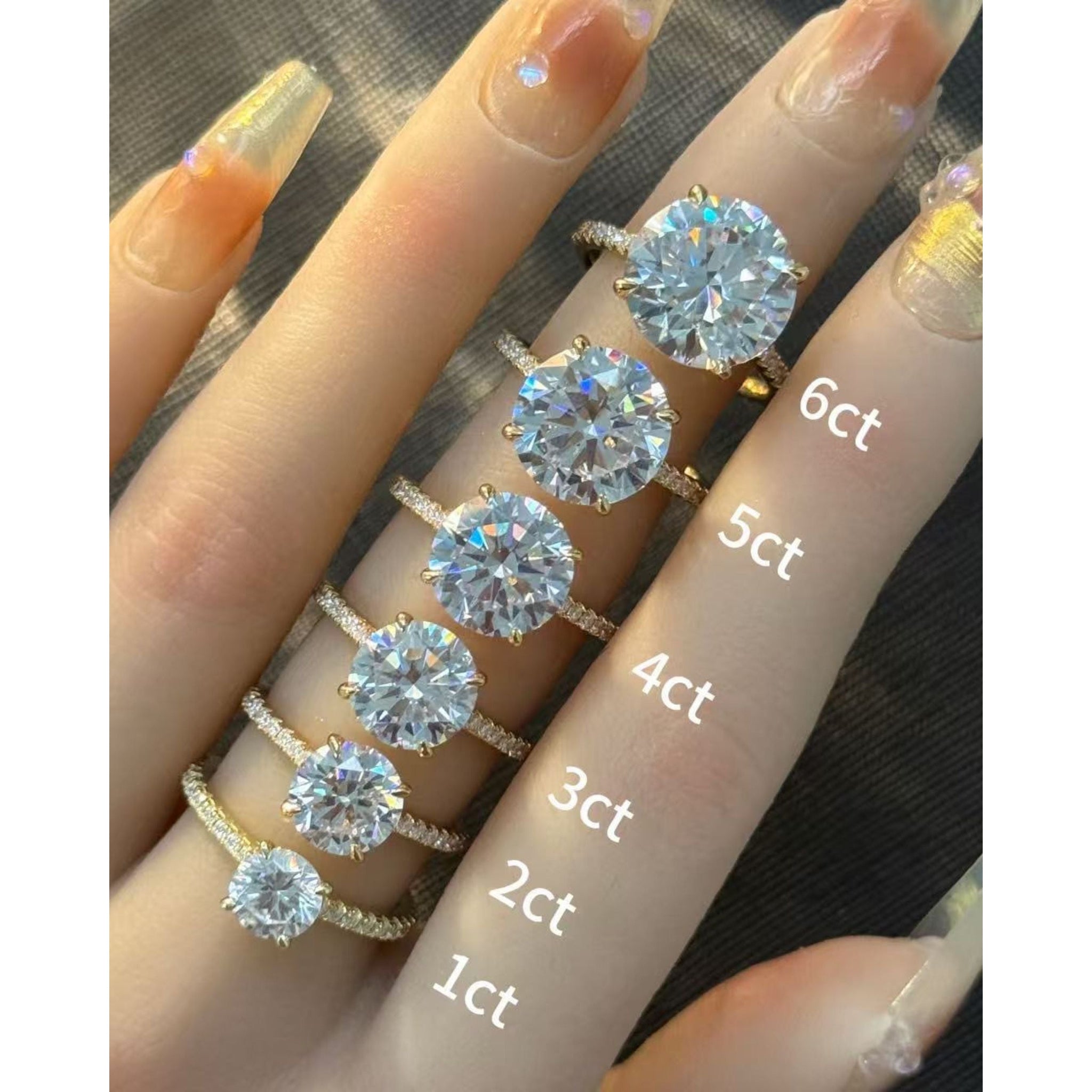 Round-cut moissanite hidden halo ring with pavé band rings arranged across fingers for a carat-size comparison.
